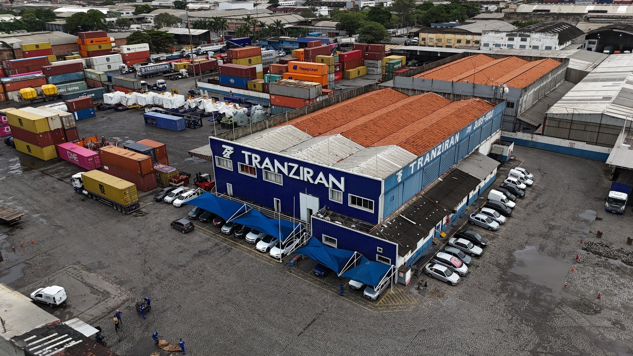 Vista aérea da sede e do terminal da Tranziran, com o nome da empresa no telhado do galpão e pátio de contêineres