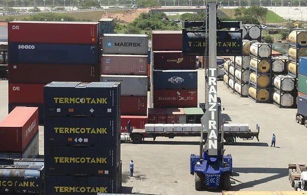Pátio do terminal com contêineres empilhados e equipamento de movimentação