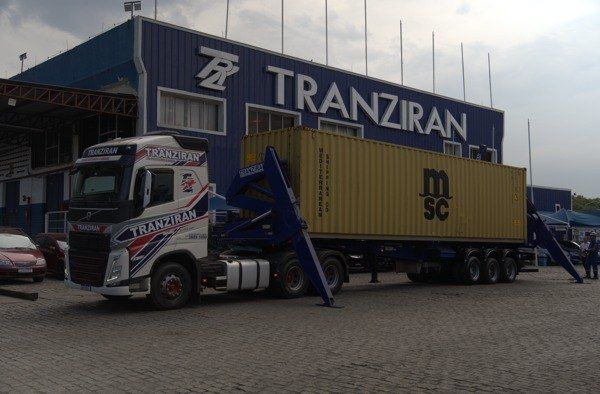 Caminhão SiderLift da Tranziran com contêiner em frente ao galpão da empresa