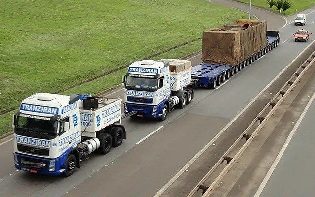 Cavalos mecânicos da Tranziran transportando carga em carreta prancha na rodovia
